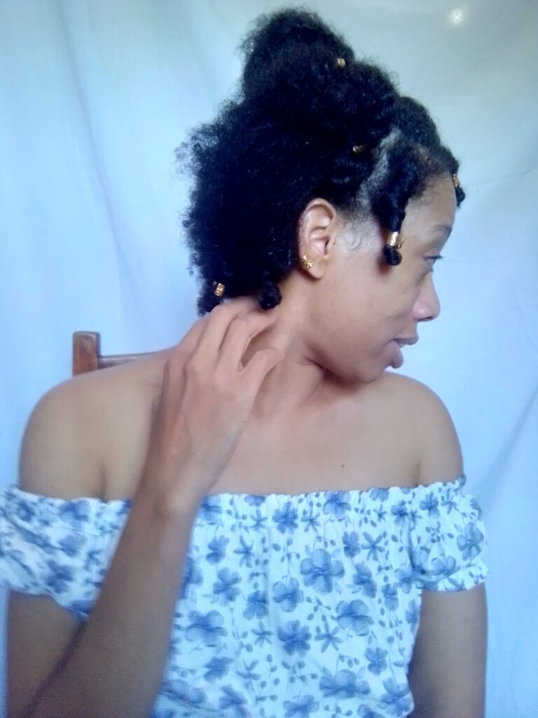 World Most beautiful lady Sher Trott Bailey showing off her amazing natural hair style in her off shoulder blouse and scratching her neck with a cute tendril with golder hair accessories.