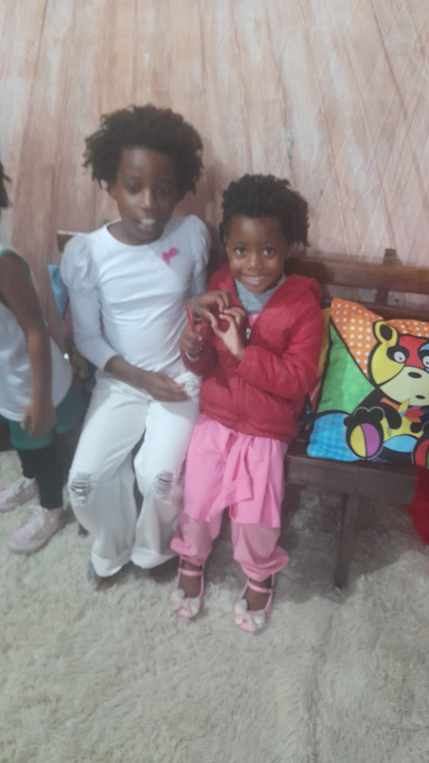 Princesses Keilah and Kaleeyon hug and make a heart with their fingers together
