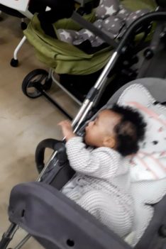 Kaleeyon sucking on her stroller and Keilah eating bread