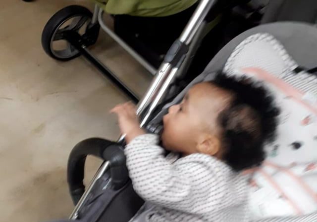 Kaleeyon sucking on her stroller and Keilah eating bread