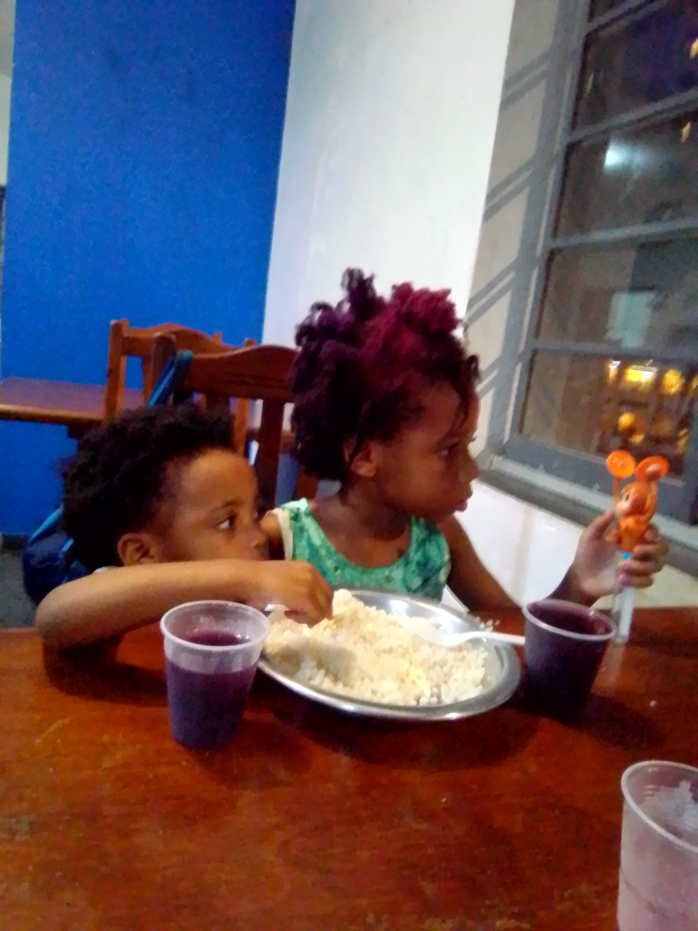 Keilah and Kaleeyon Trott Bailey eating rice from the same bowl and drinking grape juice at the cafeteria